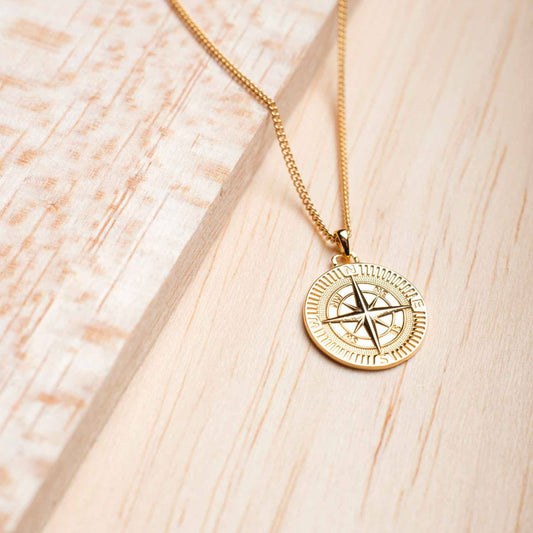 18k gold plated men's compass necklace on wooden background
