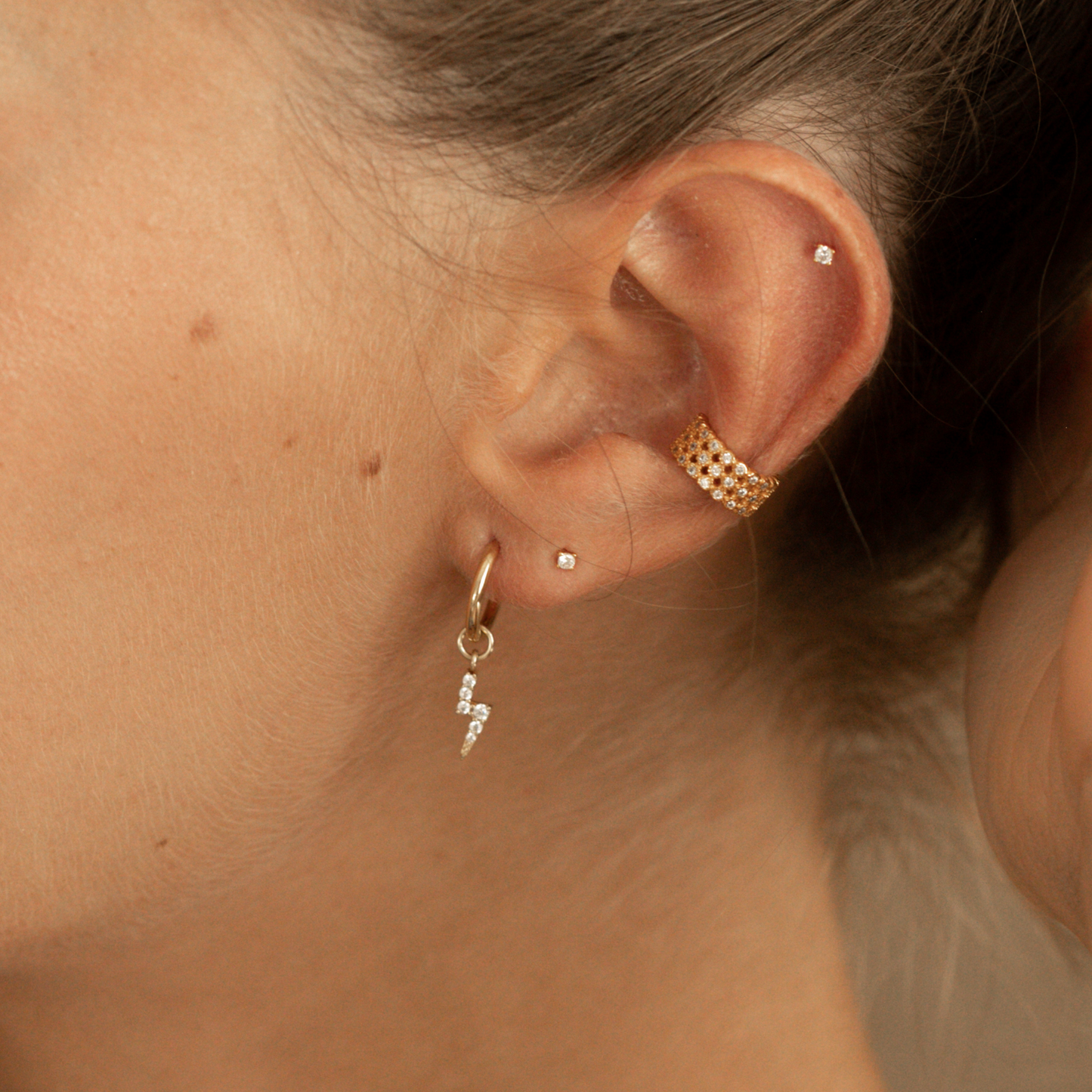 Model wearing 18k gold plated lightening bolt hoop earrings