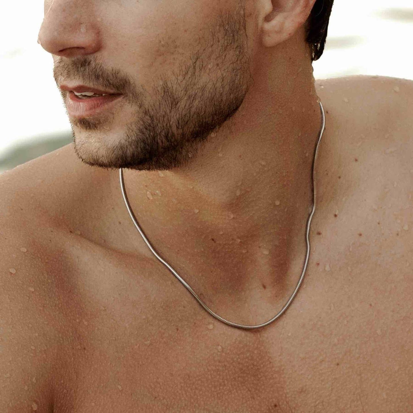 man modelling a 925 sterling silver mamba necklace on the beach