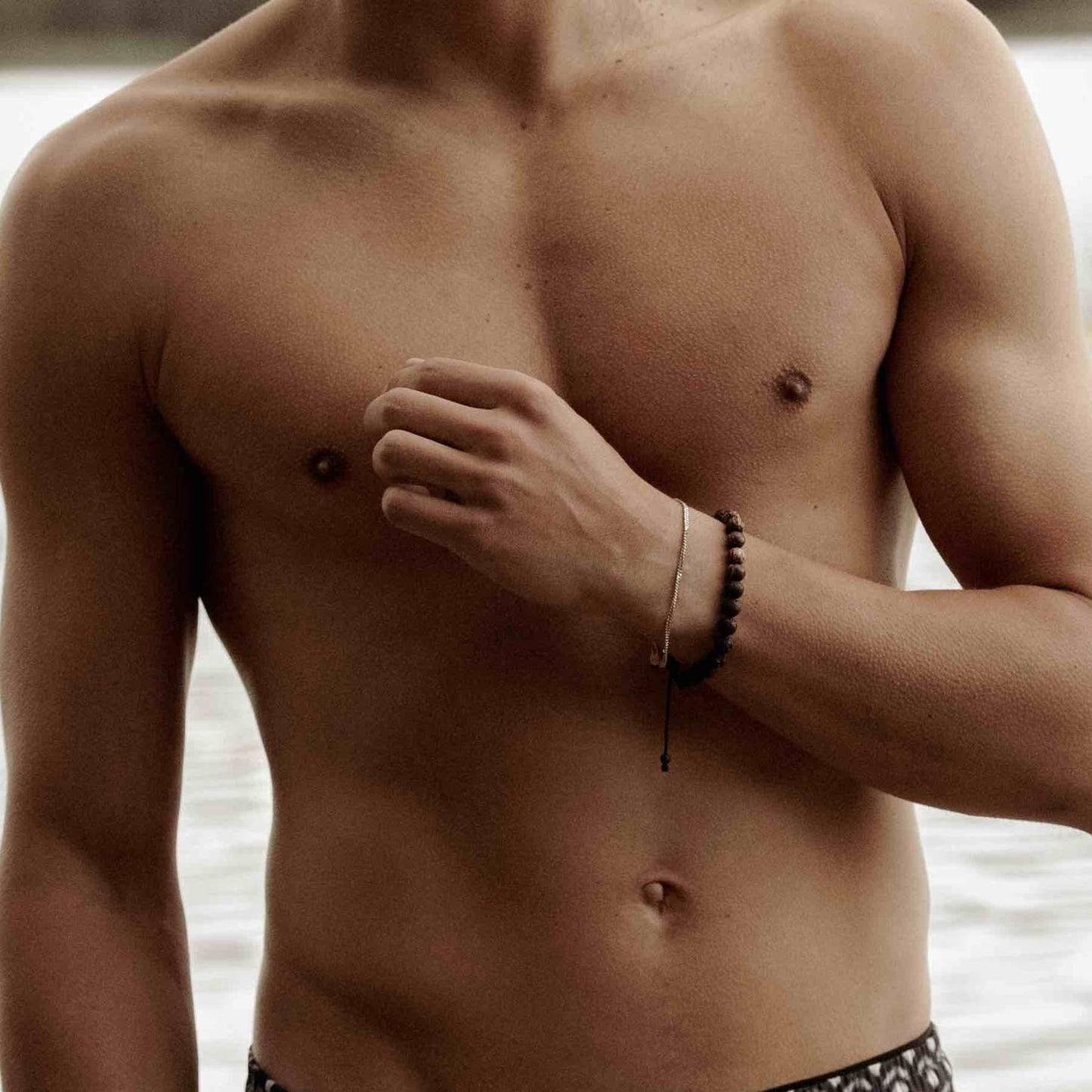man modelling an 18k gold plated men's bracelet on a beach