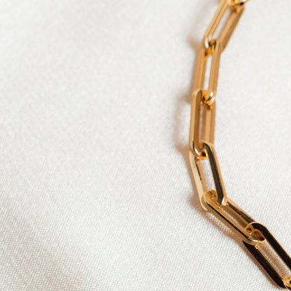18k gold-plated link chain bracelet on a light fabric background