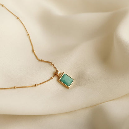 18k gold-plated necklace with a square amazonite blue gemstone pendant on a beige fabric background