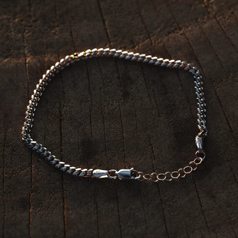 925 sterling silver Cuban chain on a dark wooden surface