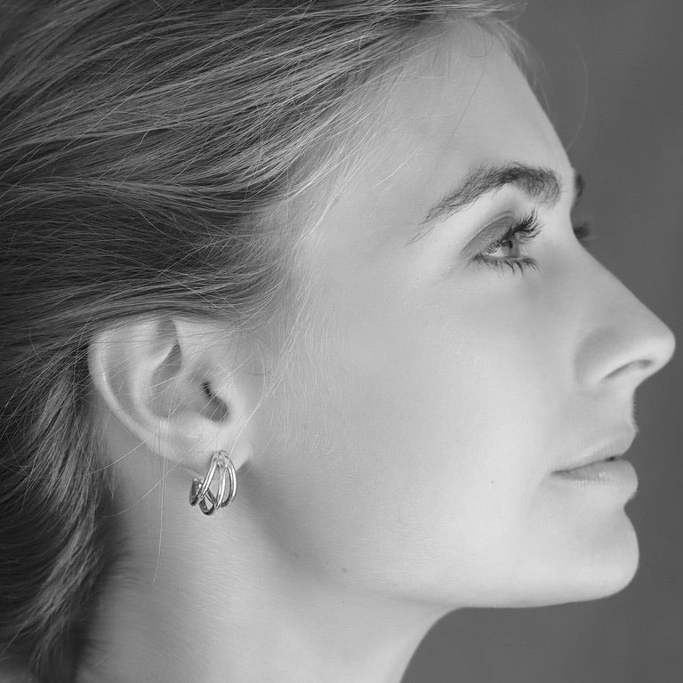 Black and white profile of a woman wearing 925 sterling silver triple hoop earrings with a blurred background