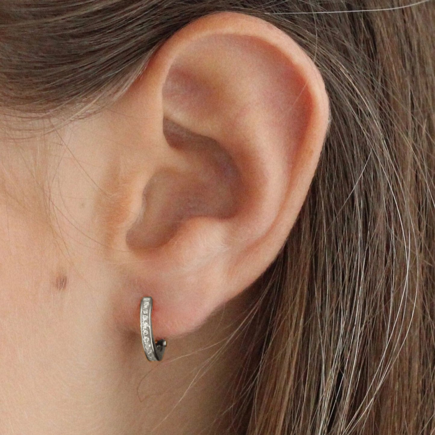 Close-up of a woman wearing a pair of 925 sterling silver hoop earrings encrusted with small zirconia