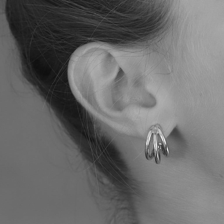Close up of a woman wearing 925 sterling silver triple hoop earrings with a blurred background