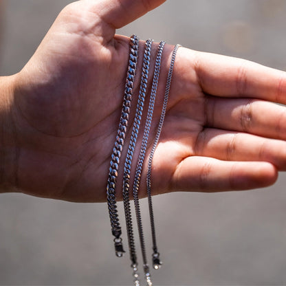 Man holding four 925 sterling silver Cuban bracelets against a blurred background