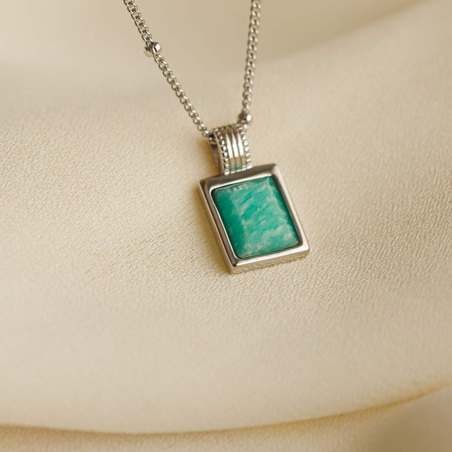 Women's 925 sterling silver necklace with blue amazonite stone pendant on a beige background
