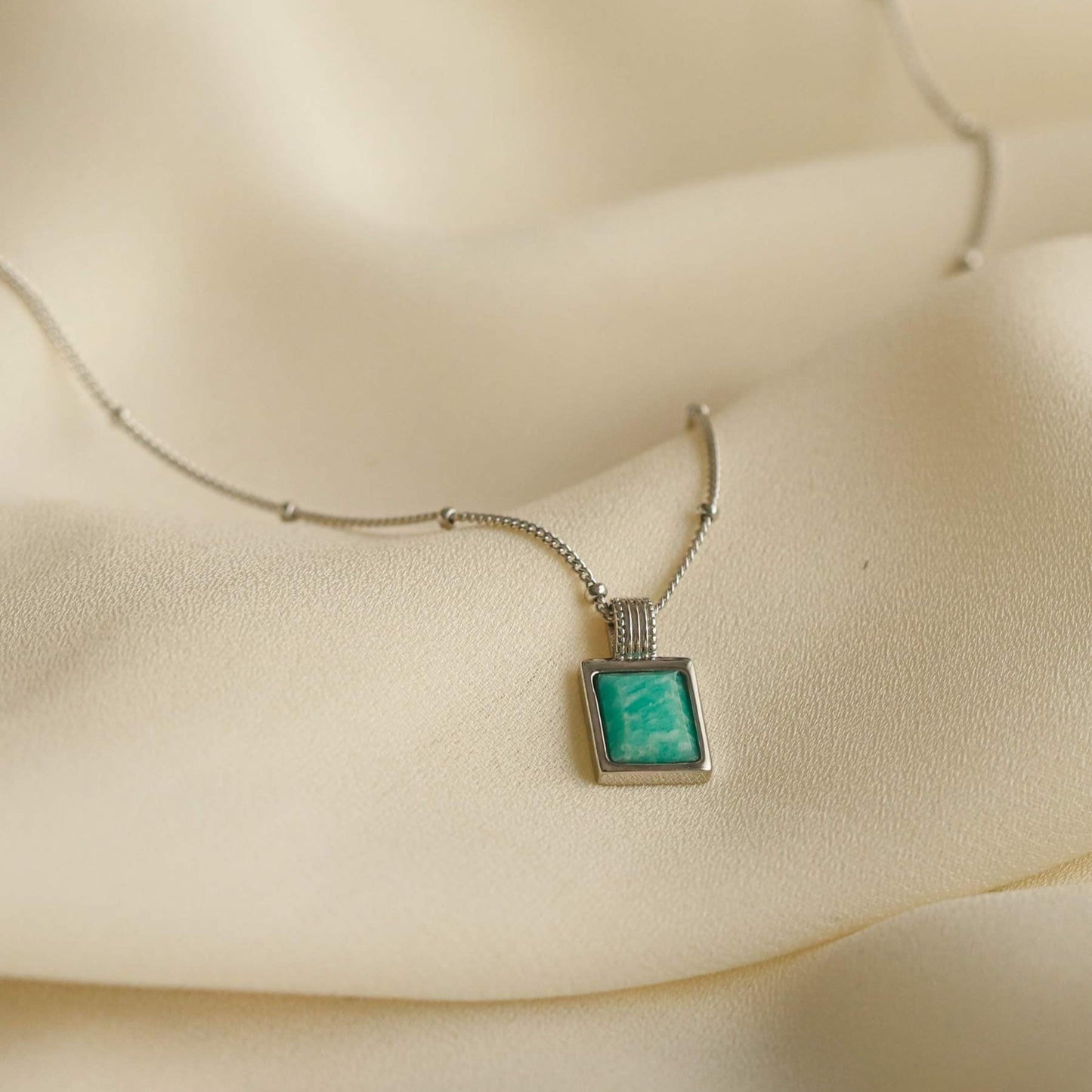 Women's 925 sterling silver necklace with blue amazonite stone pendant on a beige fabric background