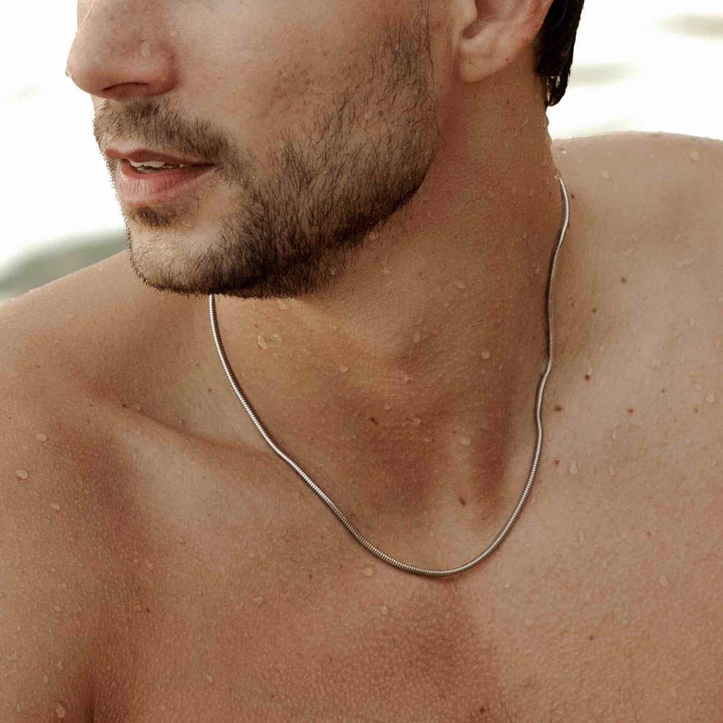 man modelling a 925 sterling silver mamba necklace on the beach
