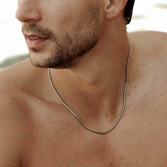 man modelling a 925 sterling silver mamba necklace on the beach