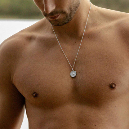 Man modelling a men's 925 sterling silver compass necklace at the beach
